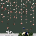 Dettaglio di ghirlande a stella in oro rosa appese davanti a uno sfondo verde scuro - 4M Stella a 4 Punte Oro Rosa