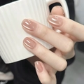 Elegant cat-eye press-on nails in pearlescent nude pink on a hand holding a ceramic cup - By1605 Fallen Leaves Tell Of Autumn / Glue Type