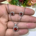 Macro view of silver necklace and stud earrings set with red square-cut zircon stones - Garnet Red