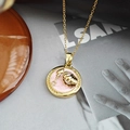Détail d'un collier doré rond avec pendentif coquillage et perle sur un magazine - Collier Pendentif Coquillage Rond - Rose