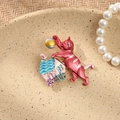 Detailed view of pink enamel cat brooch with blue house decor on a ceramic plate - Pink Cat on Roof