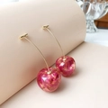 Detail of red resin cherry earrings featuring internal dried flower petals and gold stems - Cherry Style