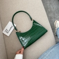 Dark green crocodile pattern underarm bag with gold zipper on gray fabric background - Green