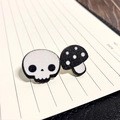 Close-up of asymmetric Halloween earrings with skull and mushroom designs on wooden base - Skull And Mushroom