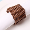 Dark brown woven rattan napkin ring with intricate texture on white cloth napkin - Rattan