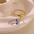 Dettaglio di anelli aperti a forma di stella in oro e argento su vassoio in ceramica - Bagliore stellare / Oro