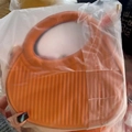 Orange saddle bag with large round handle and vertical striped texture in hand - Orange