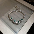 Macro detail of emerald-cut green stone bracelet with diamond halo on velvet base - 17# Silver Green Square Vintage Style