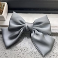 Detail of grey satin silk bow hair clip showing smooth texture and layered design - Gray
