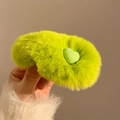 Hand holding a plush lime green faux fur hair clip with a matching green heart ornament - Green
