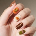 Primo piano di nail art per il Ringraziamento con motivi di tacchino e zucca sulle mani - GRAZIE Zucca Mais Ghianda (Colla a Gelatina Nera)
