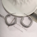 Close-up of silver C-shaped hoop earrings with twisted spiral texture on a white plate - Style D-Silver Large Twist Hoops