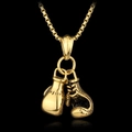 Detalle del colgante de guantes de boxeo dorados en una cadena sobre un fondo negro mate - Aleación / Dorado