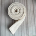 Close-up of a white wool felt belt roll with a thick fiber texture on a wooden background - Milky White