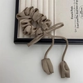 Chouchou satin beige avec long nœud et breloques en tissu sur un plateau en bois - Kaki