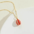 Collana dorata con ciondolo a goccia rosso e zirconi bianchi su sfondo di pietra beige - Rosso
