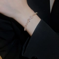 Macro shot of zircon marquise bow bracelet on model wrist with black suit sleeve - Gold Bowknot