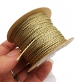 Close-up of hand-held 1mm metallic gold thread spool for DIY jewelry and crafts - Khaki