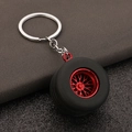 Miniature tire keychain with red multi-spoke hub on dark textured background - Red