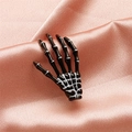 Detailed view of a black and white gothic skeleton hand hair clip on pink satin fabric - Black (8615)