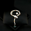 Detailed view of a silver snake brooch with enamel, white pearl, and green drop pendant - Orange Enamel Snake