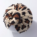 Close-up of leopard print baby turban hat with top knot detail on a white mannequin - Style A (Brown Leopard)