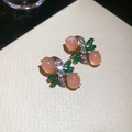 Dettaglio di orecchini dorati con pietra in resina rosa e intarsio di strass a foglia - Orecchini ad Ago in Argento - Rosa - Verde