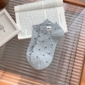 Socquettes gris clair à pois foncés avec étiquette Nice posées sur un livre - Taille unique / Gris clair