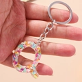 Close-up of letter Q keychain featuring colorful glitter inside clear resin material - Letter Q