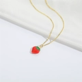 Collar minimalista dorado con colgante de fresa roja sobre un fondo de seda blanca suave - Fresa