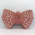 Close-up of pink bow clutch bag featuring dense rhinestone embellishments and gold hardware - Pink