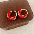 Detalle de pendientes de aro con cuentas rojas sobre un joyero de terciopelo marrón - Dorado/Rojo