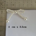 Macro detail of pearl bow accessory with scale showing dimensions 4cm x 3.5cm - 48-Pearl Bow