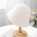 Detailed knit texture of a cream hollow-out bucket hat on a wooden display stand - One Size / White