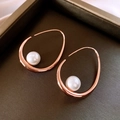 Macro detail of rose gold geometric earring with white pearl inlay on luxury display - Rose Gold Irregular Oval Loop Pearl Earrings