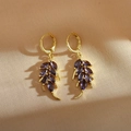Macro shot of gold wheat-leaf earrings with marquise-cut purple stones and secure clasps - Purple
