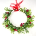 Detail eines Weihnachtskranzes mit grünen Blättern, roten Beeren und roter Schleife - Weihnachten Rote Beeren Stil