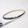 Cintura sottile in pelle nera con fibbia rettangolare dorata posata su un libro minimalista - Nero