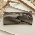 Detail eines braunen Strick-Stirnbands mit Knotendesign auf einem beigen Tablett - Hellkaffee