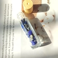Essential oil roller bottle with wooden cap and blue crystal stones inside on a book - Lapis Lazuli