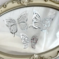 Detailed view of three silver hollow butterfly cake toppers placed on a vintage gold frame - Style 3 / Set of 12 / Silver