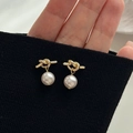 Elegant gold knot earrings with white round pearls displayed on a black knit background - Gold Knot White Pearl