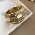 Detailaufnahme von geometrischem Goldmetall und Marmor-Acryl-Gliedern am Armband - Hellkaffee
