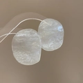 Macro detail of irregular resin earrings with ice crack texture and silver needles - White