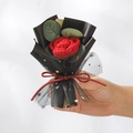 Handgestrickter roter Rosenstrauß in schwarzem Netz mit goldenen Sternen - Gestrickte rote Rose