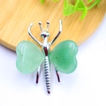 Macro shot of butterfly pendant with green heart-shaped gemstones on wooden plate - White K Plated Green Aventurine