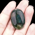 Oval moss green agate stone with natural inclusions and a polished translucent finish - India Agate