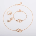 Dettaglio del set di gioielli dorati con design a doppio cuore intrecciato e strass lucidi - Set da 4 pezzi / Oro rosa