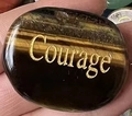 Oval tiger eye power stone featuring engraved courage text on a polished surface - Tiger's Eye