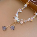 Dettaglio macro di perle iridescenti e ciondoli a fiore bianco su un orecchino elegante - Collana di fiori in cristallo rosa